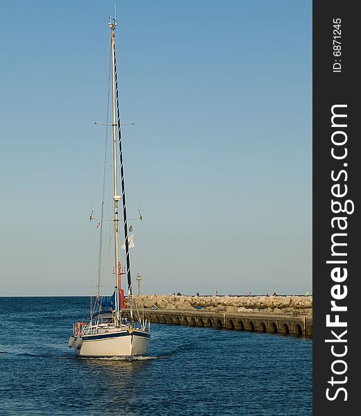 Sailboat moving to moorage in a port. Sailboat moving to moorage in a port