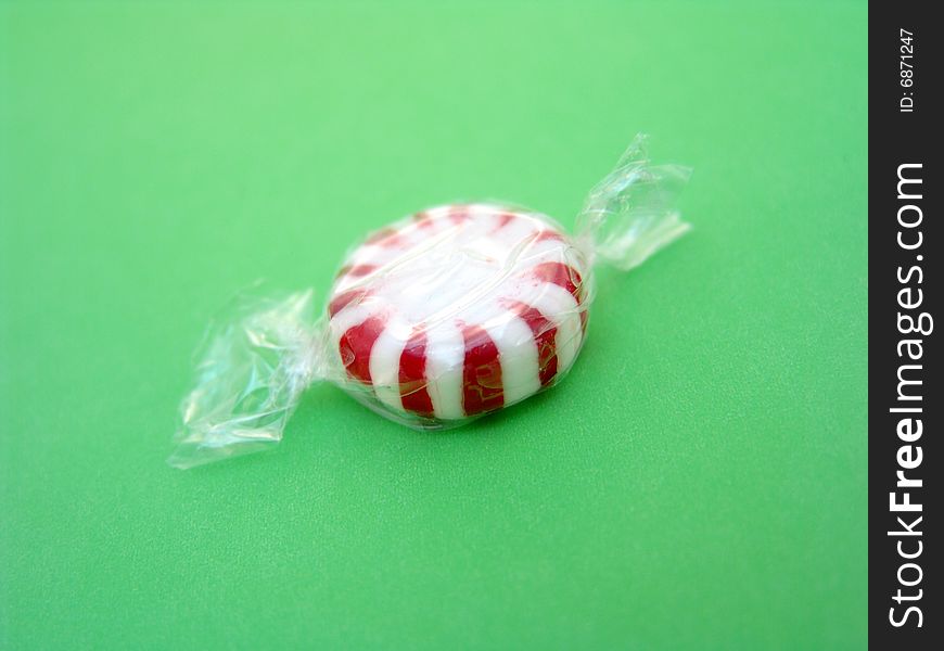 Red and white peppermint isolated over green background. Red and white peppermint isolated over green background