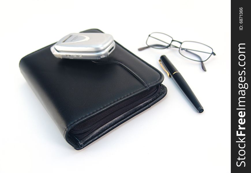 Black leather planner, pen, silver cell phone over white. Black leather planner, pen, silver cell phone over white