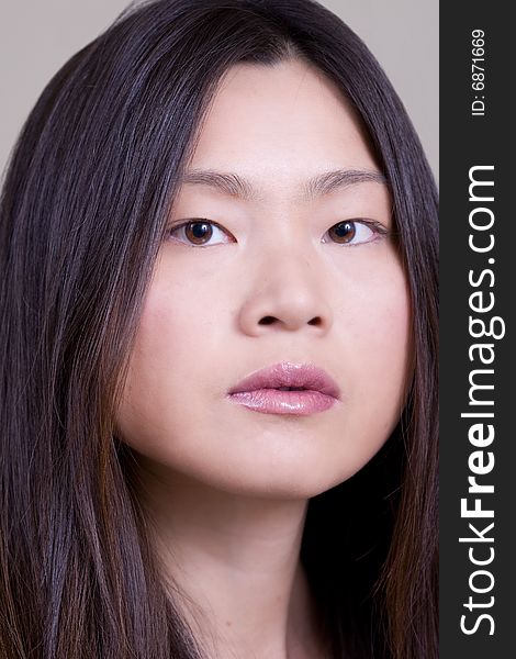 Portrait of young Asian woman shot at a studio with off-white background