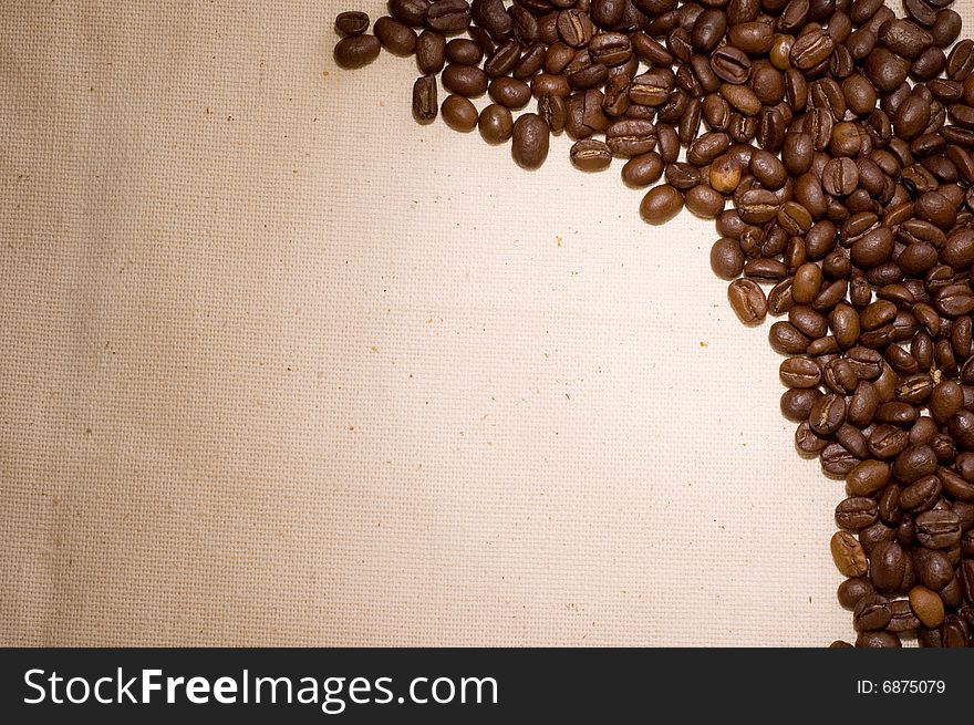 The coffee grains spilted on the sackcloth for background. The coffee grains spilted on the sackcloth for background