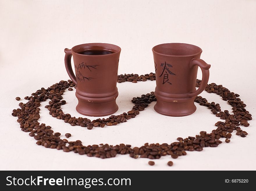 Two cups of coffee stand in a in the yin yang symbol.
One cup is empty.