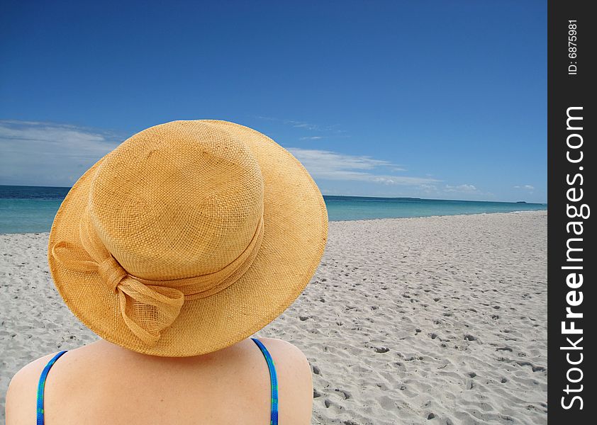 Woman in hat sit on ocean beach