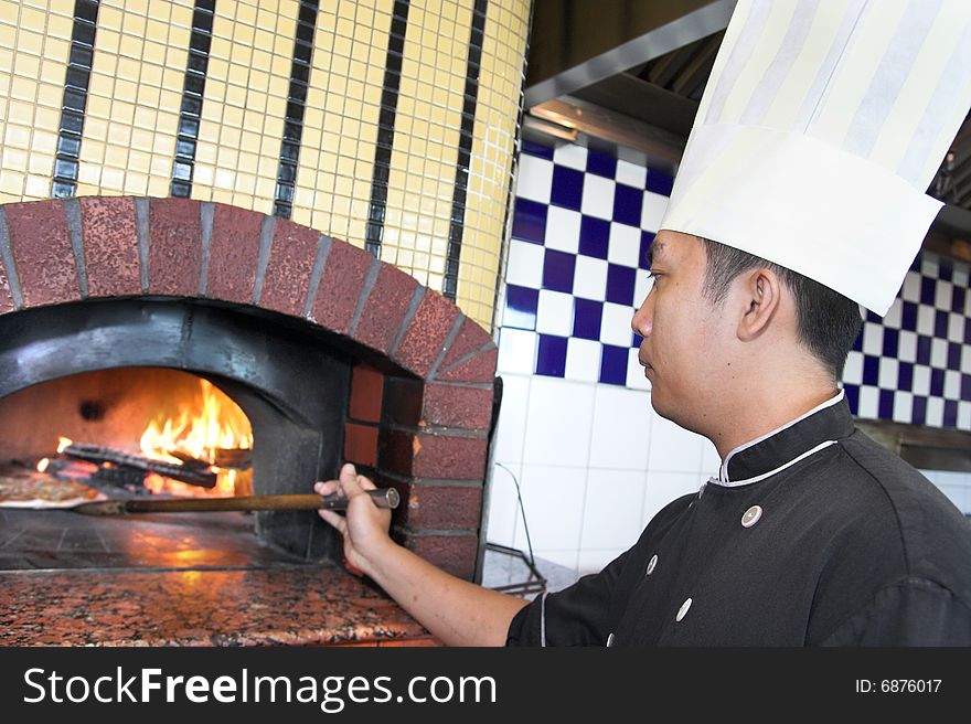 Chef cooking pizza in oven. More photos of this series HERE