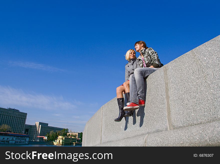 Two young girls sitting on a concrete board. Two young girls sitting on a concrete board