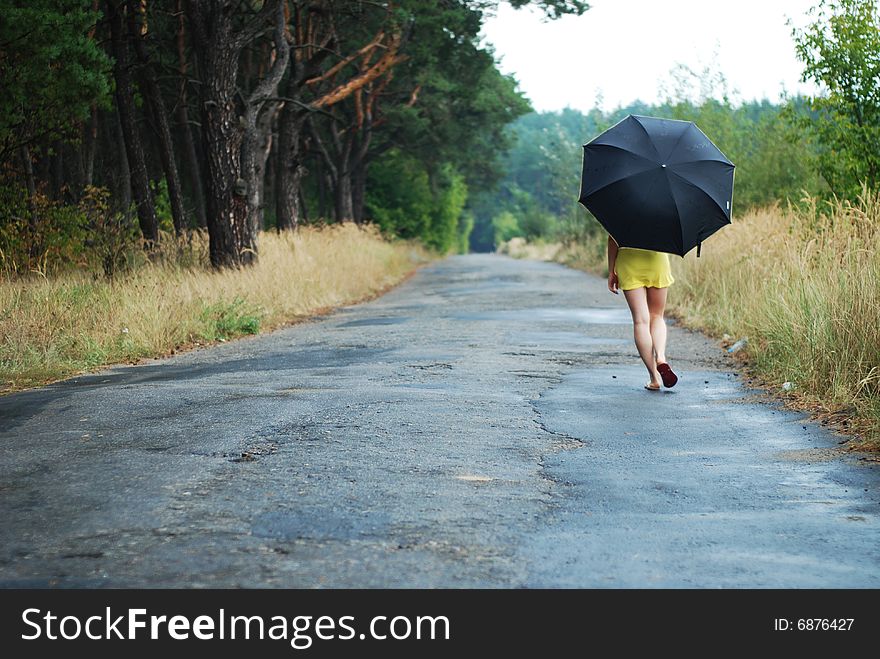 Young woman with black umbrella walking in park on a rainy day. Young woman with black umbrella walking in park on a rainy day