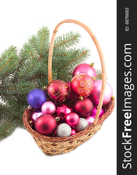 Yellow basket with New Year's spheres and green branch of fur-trees on white background