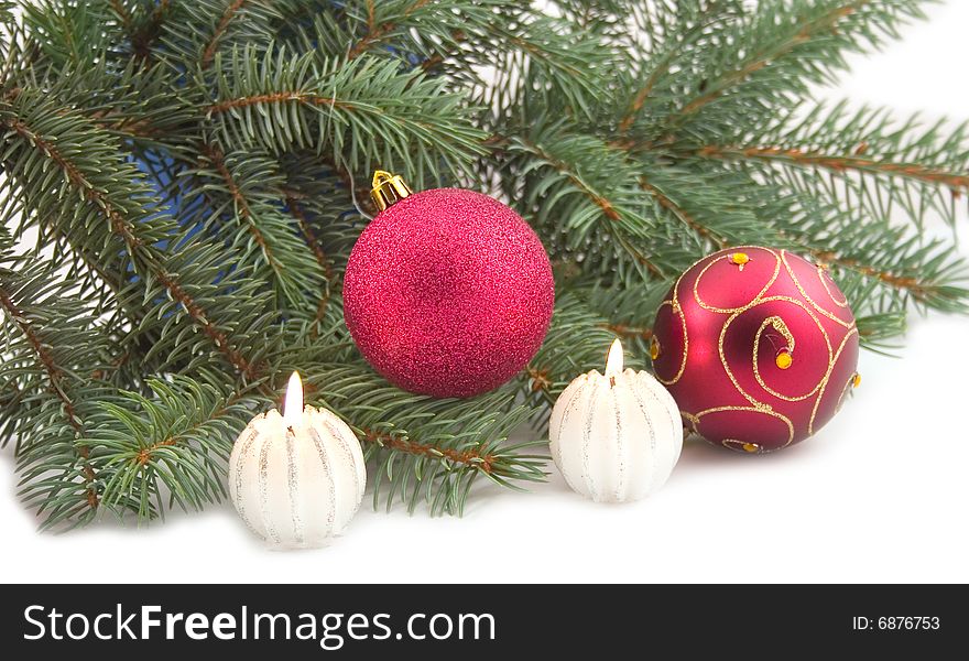 Decorative burning candles with New Year's spheres and green branch of fur-trees on white background