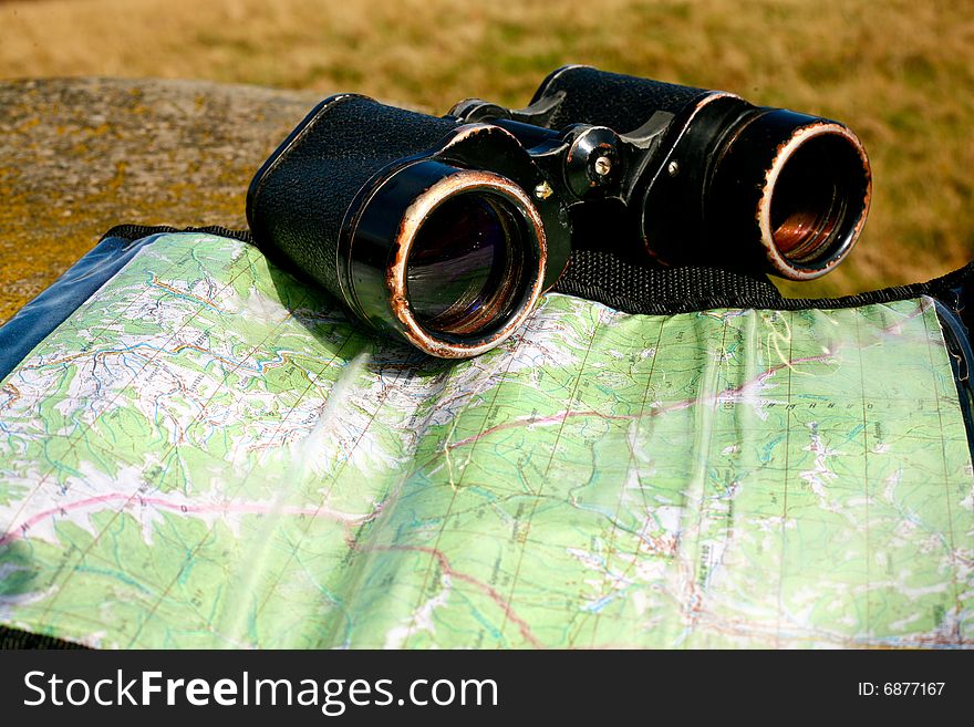 An image of binoculars and map on dry grass. Adventure theme. An image of binoculars and map on dry grass. Adventure theme