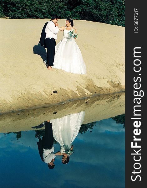 A couple after their wedding in the early morning, on a sand dune beside a lagoon. A couple after their wedding in the early morning, on a sand dune beside a lagoon.