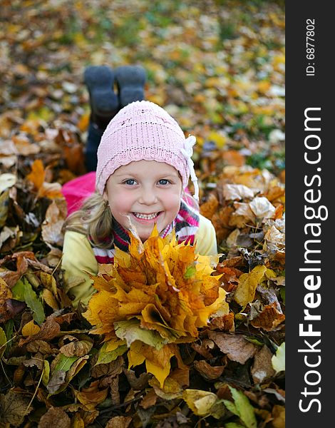 An image of little girl with yellow leaves in autumn park. An image of little girl with yellow leaves in autumn park