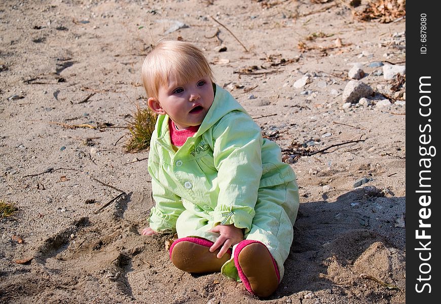 Baby sits on sand at autumn