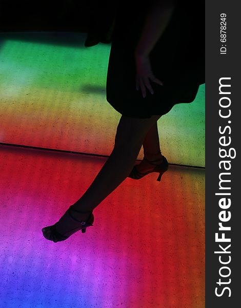 Colorfully lit dance floor, with human silhouettes in motion, dancing