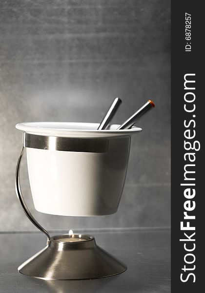A white fondue set with a candle.