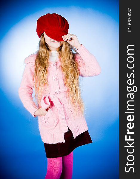 Funny little girl putting on red cap, studio shot