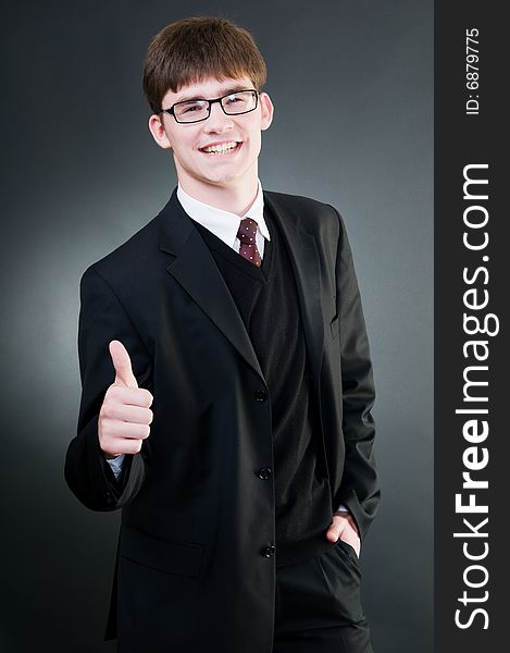 Young handsome businessman showing thumbs up, isolated on black background