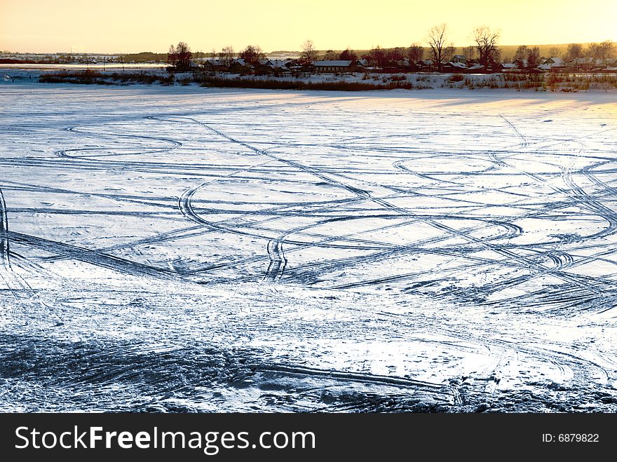 Tracks on frozen river with sunset