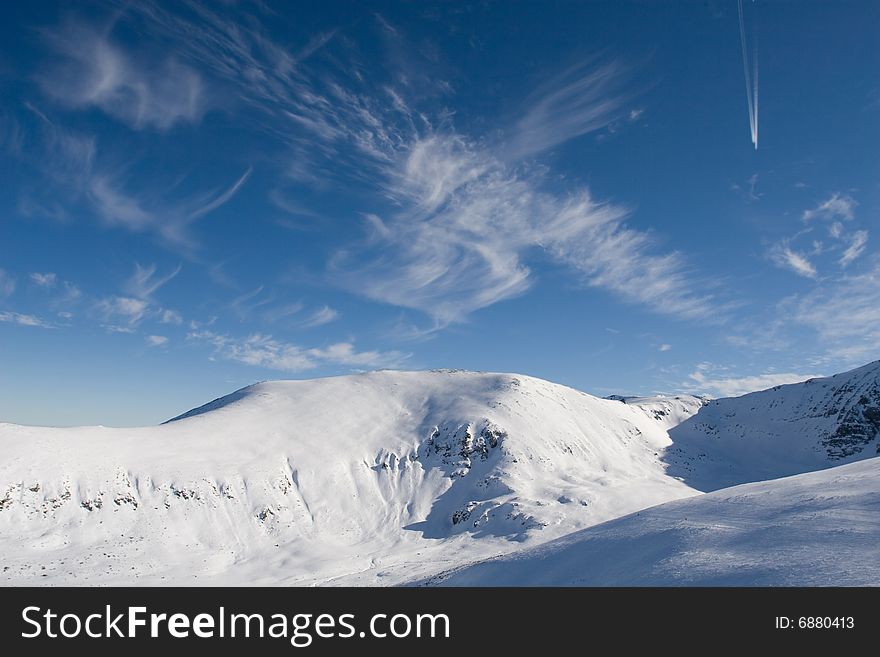 Snowy mountain cliffs touching the blue winter sky. Snowy mountain cliffs touching the blue winter sky