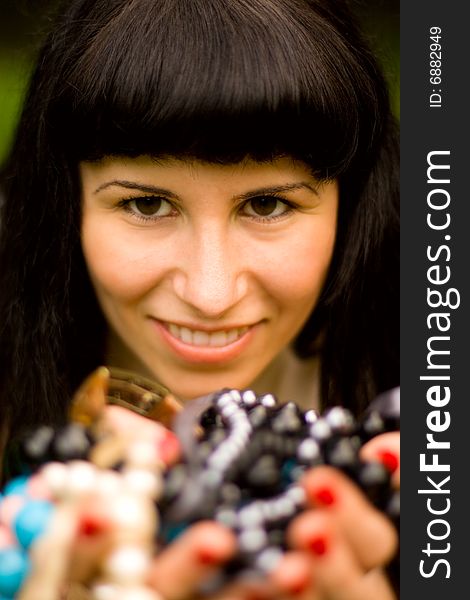 Closeup portrait on young brunette holding a lot of beads