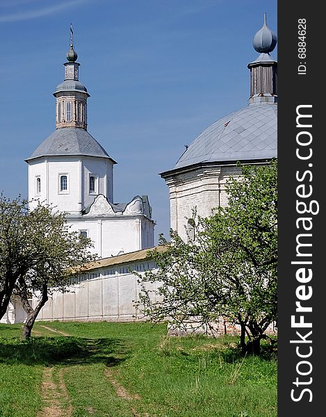 Tower and cathedral of orthodox monastery among apple trees garden  in russian province at sunny may day. Tower and cathedral of orthodox monastery among apple trees garden  in russian province at sunny may day