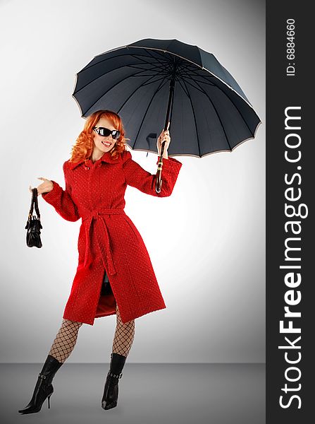 Portrait of the stylish young woman with an umbrella in a red coat