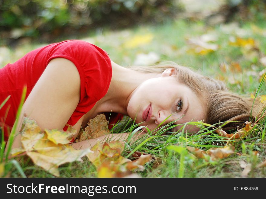 Beautiful young woman lying on the grass with yellow leaves. Beautiful young woman lying on the grass with yellow leaves
