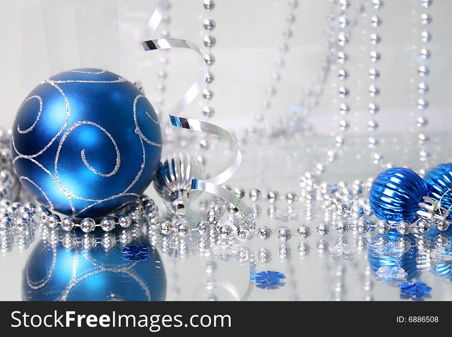 A lovely blue baubles on a mirror  surface with ribbons and beads. A lovely blue baubles on a mirror  surface with ribbons and beads.