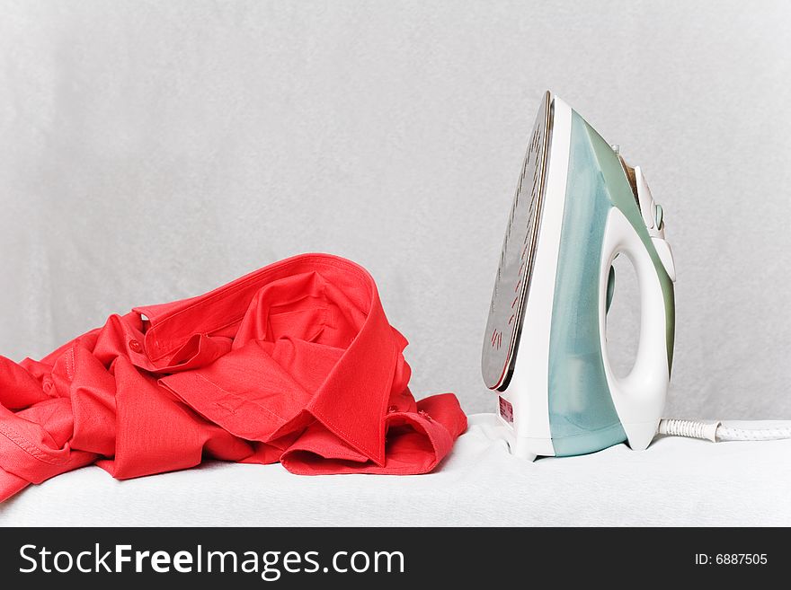 Iron on the table with red shirt