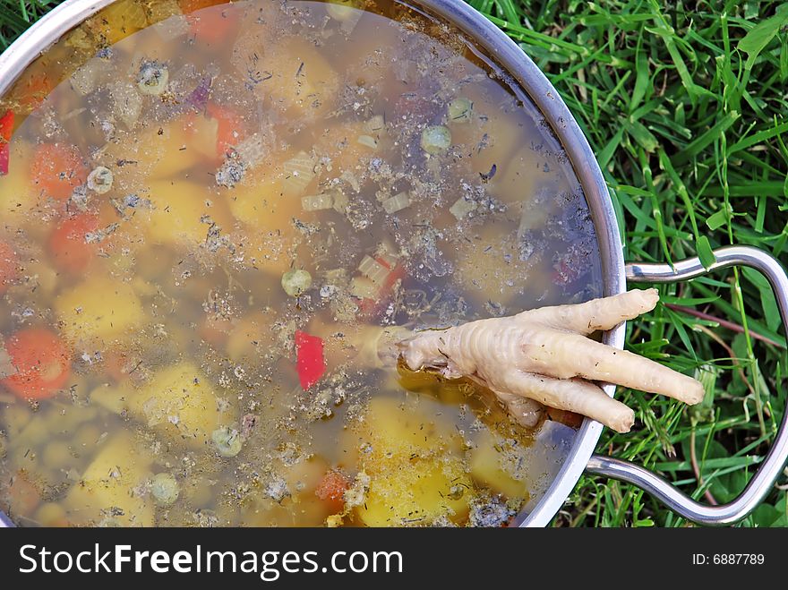 Soup in pot with vegetables outdoor with chicken leg. Soup in pot with vegetables outdoor with chicken leg