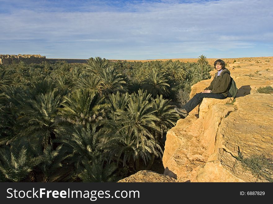 Young woman sits above oasis in African desert, Source Bleue de Meski, Morocco. Young woman sits above oasis in African desert, Source Bleue de Meski, Morocco