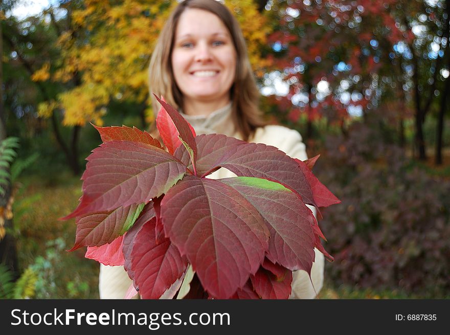 Young woman holds bouquet of autumnal leaves