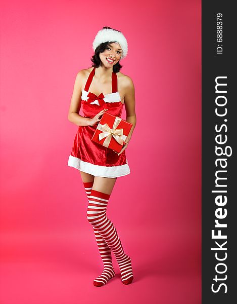 Winter portrait of a smiling christmas woman in front of a pink background with a gift. Winter portrait of a smiling christmas woman in front of a pink background with a gift