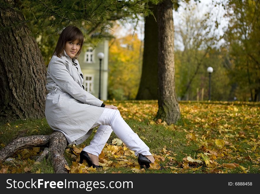 Young woman sits in autumn park. Focus on the face. Vertical version in my portfolio. Young woman sits in autumn park. Focus on the face. Vertical version in my portfolio.