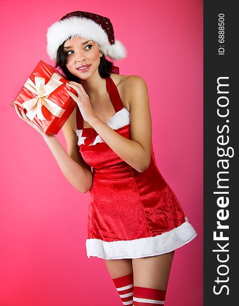 Winter portrait of a smiling christmas woman in front of a pink background with a gift. Winter portrait of a smiling christmas woman in front of a pink background with a gift