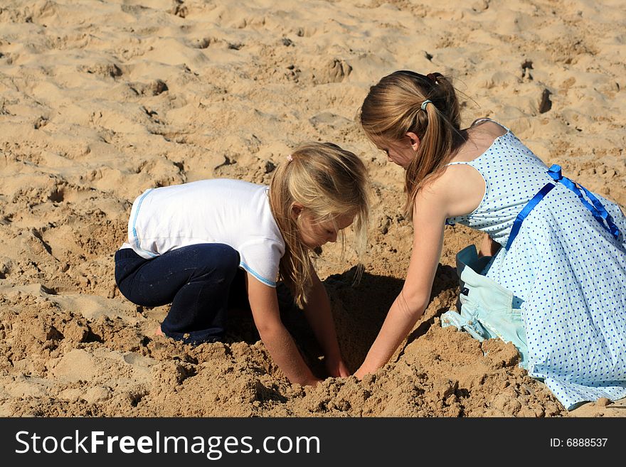 Two white caucasian girl children playing in the sand on a hot summers day. Two white caucasian girl children playing in the sand on a hot summers day