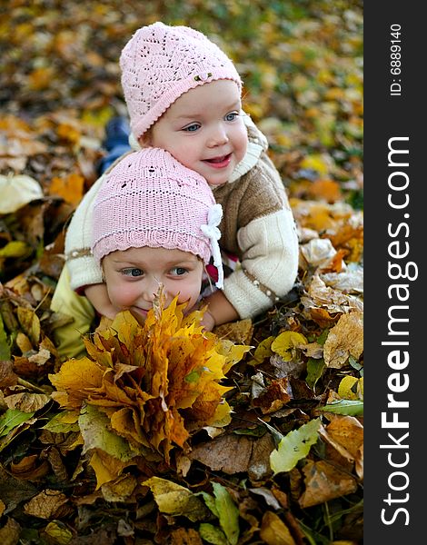 Two sisters playing with yellow leaves in a park. Two sisters playing with yellow leaves in a park