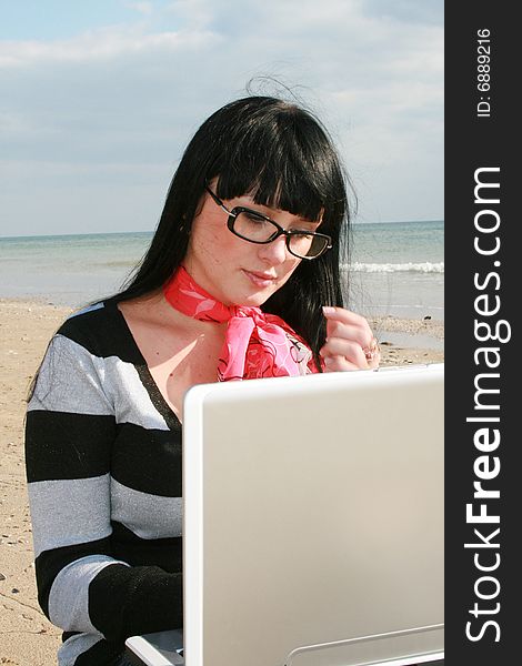 Young woman with computer at the beach. Young woman with computer at the beach