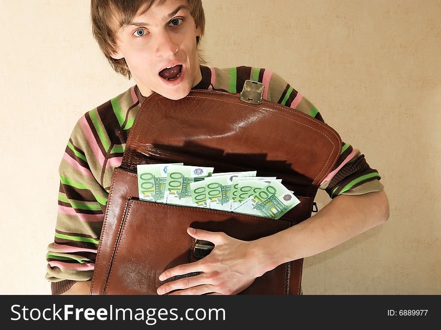 Young man in casual clothes with briefcase full of money. Young man in casual clothes with briefcase full of money