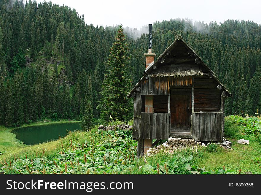 The wood cabin in Julian Alps with the small lake and forest against a background