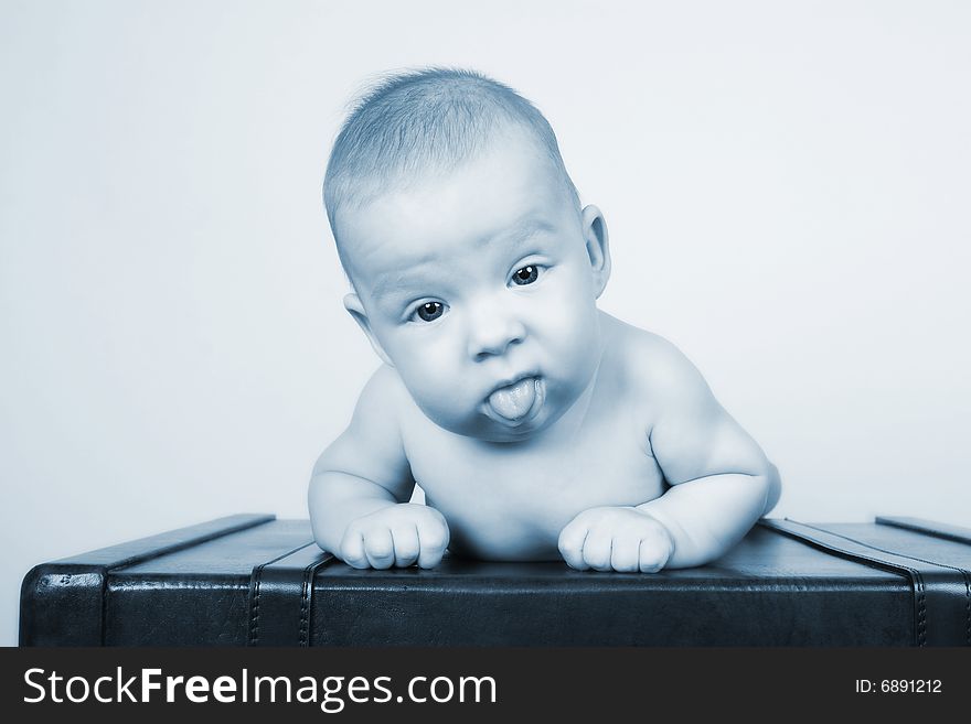 Young baby lying on his tummy on an old style suitcase