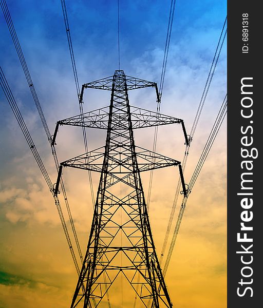 Silhouette of electricity pylon with blue and yellow sky