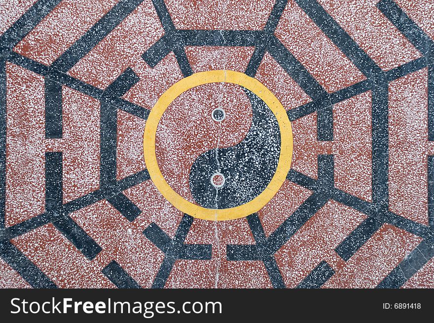 A yin yang Chinese symbol in black, yellow and red granite