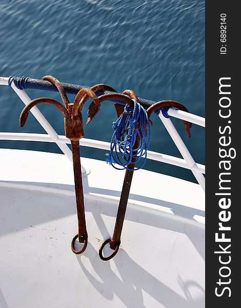 Two rusty anchors are hanging on a yacht handrail. Two rusty anchors are hanging on a yacht handrail