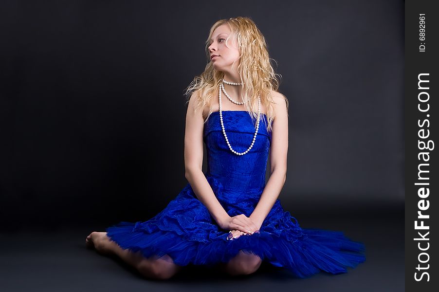Beautiful girl in a dark blue dress and a pearl necklace on a black background. Beautiful girl in a dark blue dress and a pearl necklace on a black background