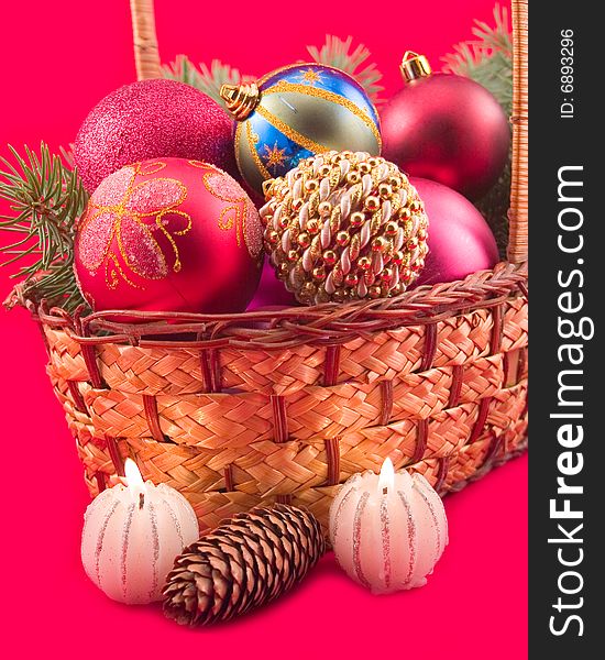 Burning candles at yellow basket with fruit and New Year's spheres on red background. Burning candles at yellow basket with fruit and New Year's spheres on red background