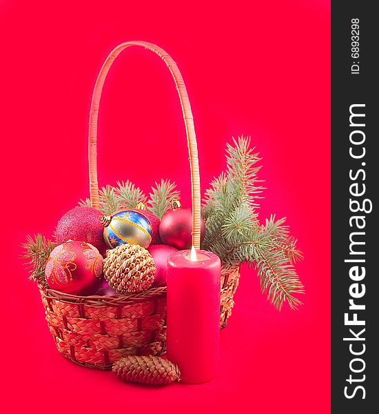 Red background with red candle and New Year's spheres in yellow basket with green branch