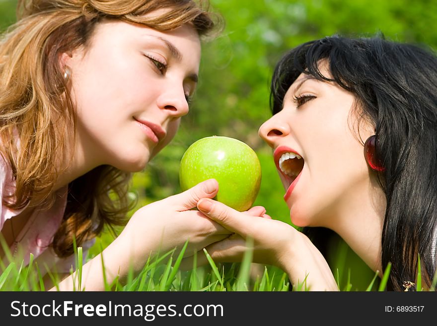 Pretty women eating green apples on the summer glade