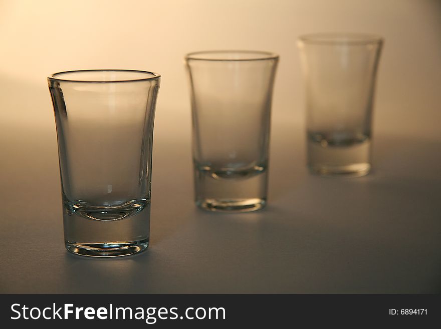 Three liquor glasses, simple brown background, distance blur. Three liquor glasses, simple brown background, distance blur