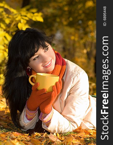 Young pretty woman with tea cup in the autumn park