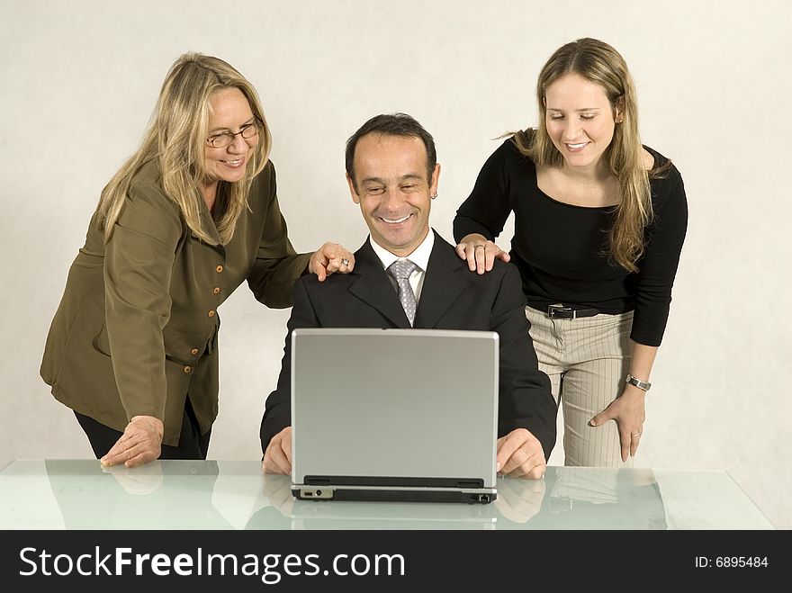 Three people are in a business meeting. They are smiling and looking at the screen of the laptop. Horizontally framed shot. Three people are in a business meeting. They are smiling and looking at the screen of the laptop. Horizontally framed shot.